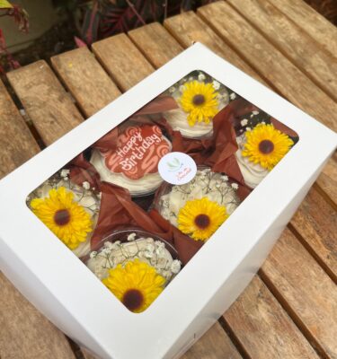 Pack de 6 cuchareables decorados con girasoles amarillos, flores blancas y mensaje personalizado de cumpleaños, presentados en una elegante caja blanca con ventana transparente.
